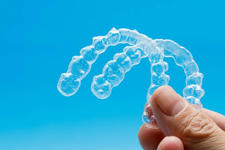 hand holding two transparent retainers on blue background invisalign orthodontics concept