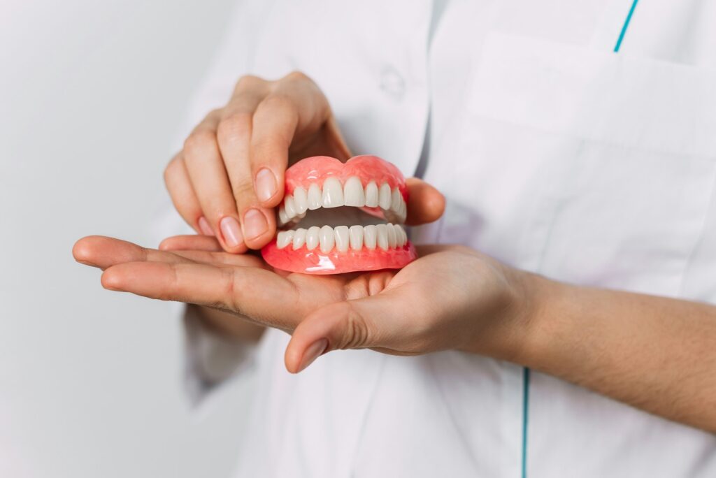 the dentist is holding dentures in his hands dental prosthesis in the hands of the doctor