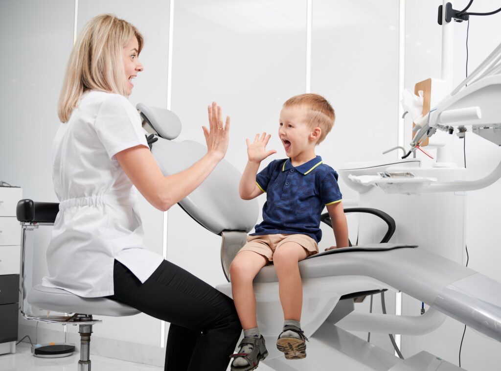 happy kid at dentist office giving high five to a dentist