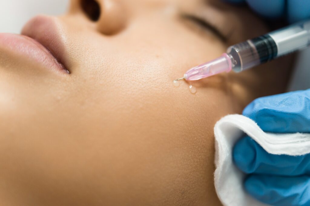 close up view of a beautician hands injecting hyaluronic acid into a patient s cheek
