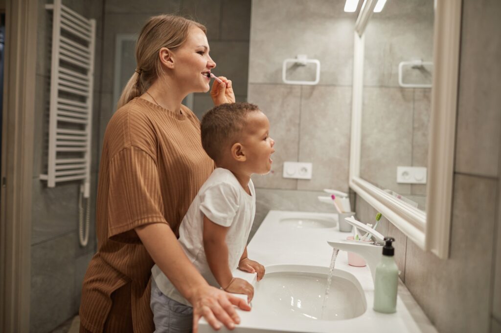baby boy brushing teeth with mom