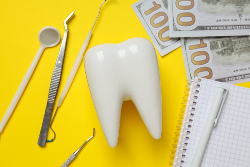 dental tools money decorative tooth and notepad on yellow background closeup