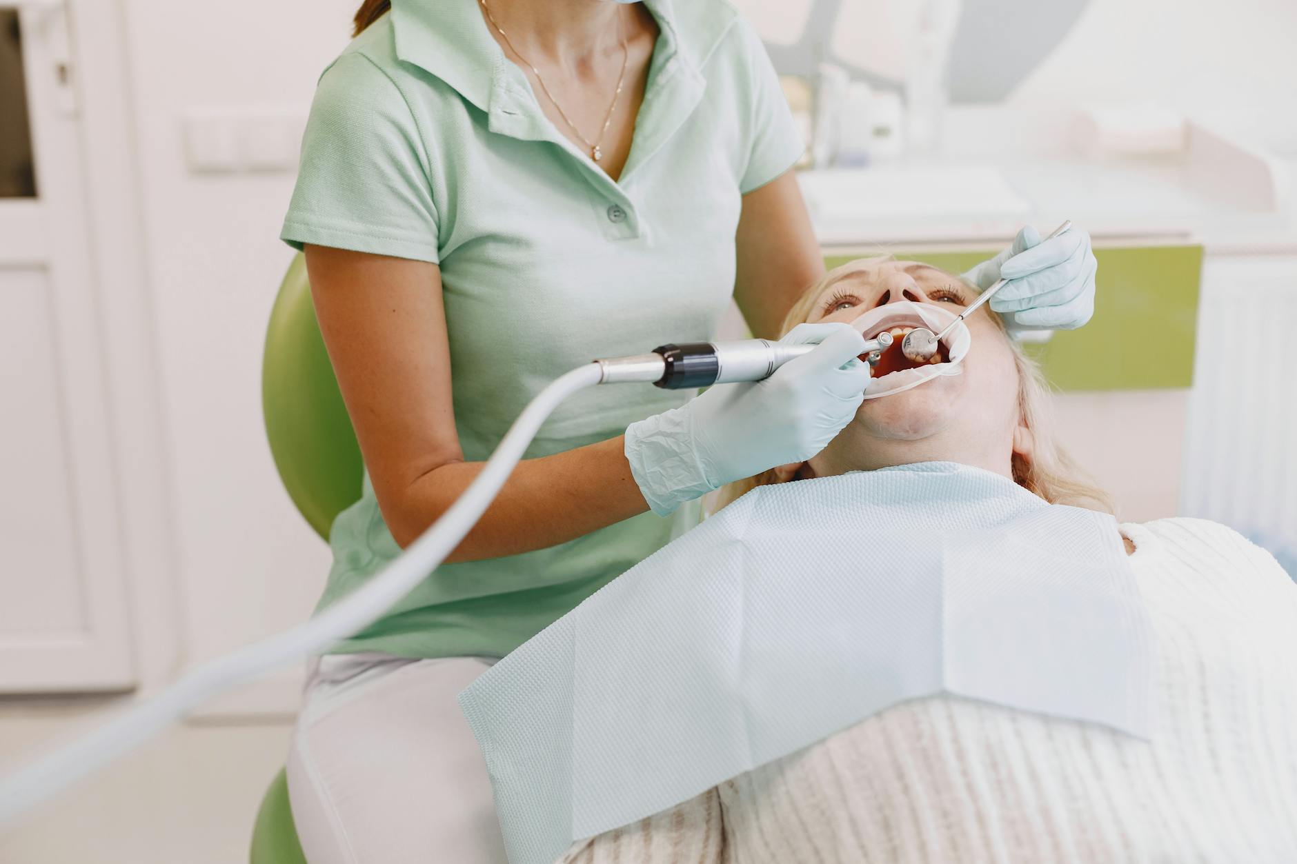 dental hygienist cleaning patient teeth professional setting